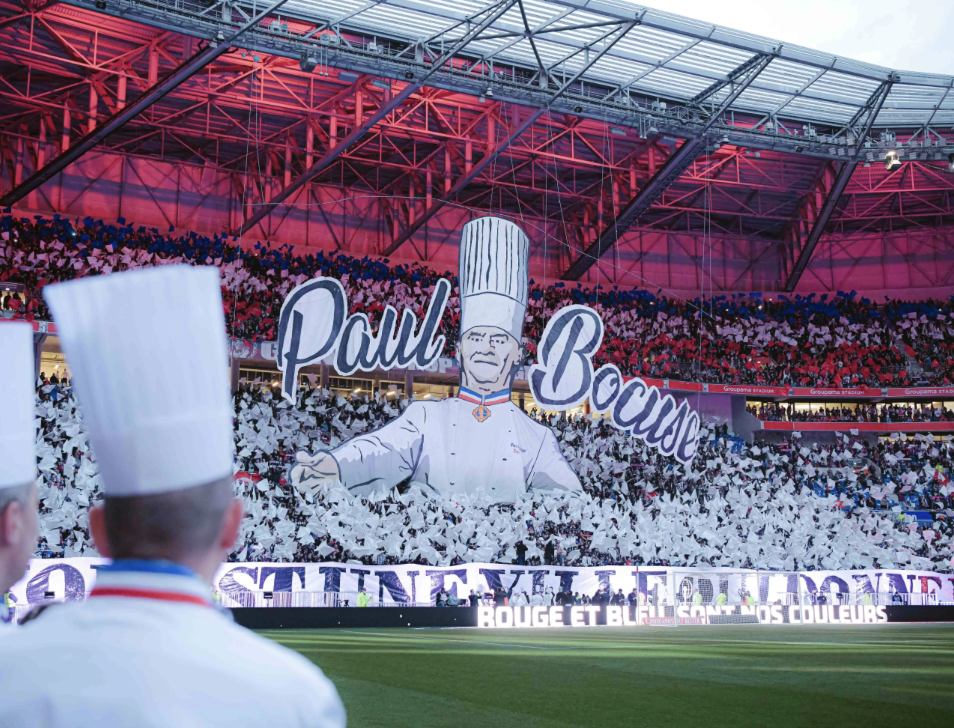 Capture d’écran 2025-10-09 à 10.57.59 "Tifo de Paul Bocuse, brandit par les supporters, au stade du Groupama stadium, de l'Olympique Lyonnais